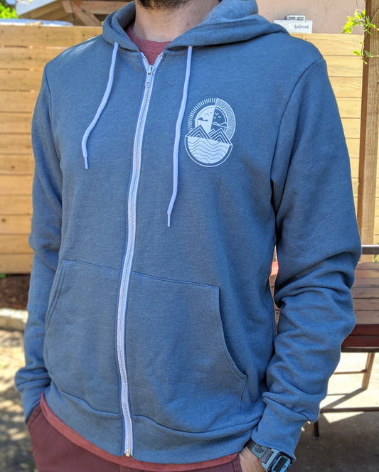 Person wearing a blue hoodie with a logo, standing outdoors.