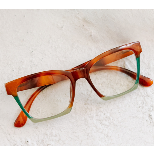 Brown and green eyeglasses on a textured white surface