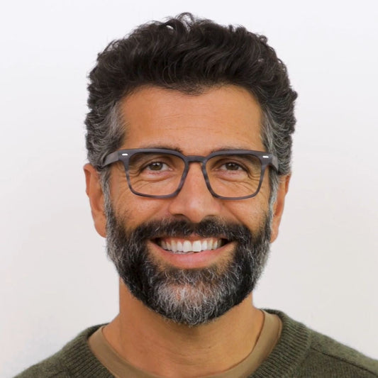 Man with glasses and a beard smiling against a white background