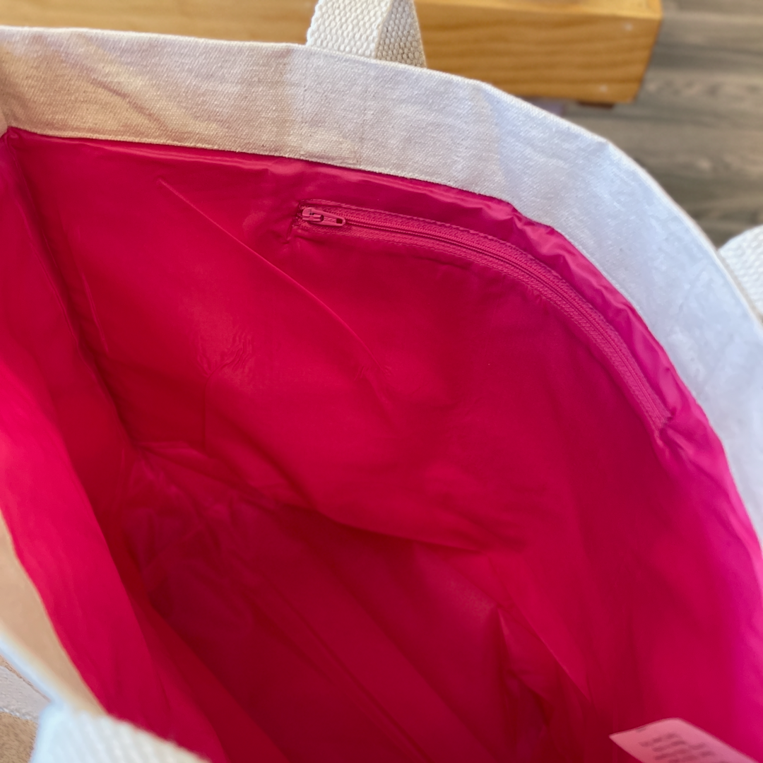 Pink interior of canvas tote. Features zippered interior pouch.