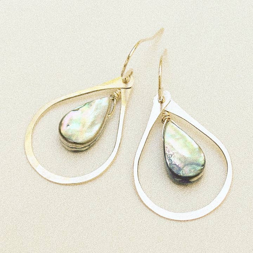Teardrop-shaped earrings with abalone on a beige background