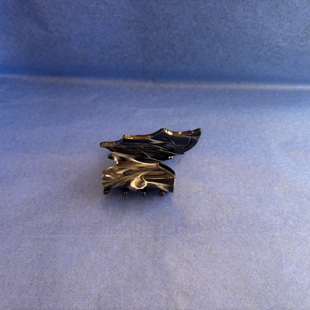 A plastic bat shaped claw clip on its side