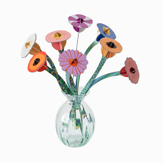 Colorful cardboard flowers in a clear glass vase on a white background
