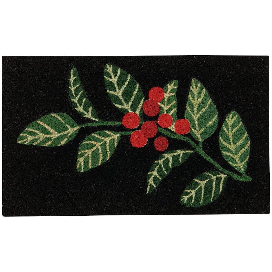 A rectangular black doormat featuring a raised green holly leaf and branch design with red berries, shown against a plain white background.