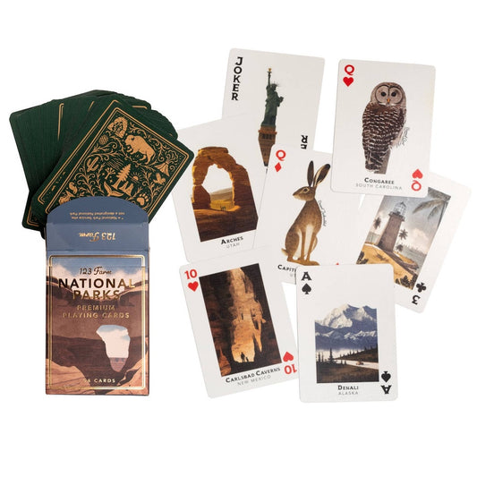 National Parks playing cards set with a blue and brown illustrated box, a fanned deck of green-backed cards, and several sample cards showing national park illustrations on a white background.