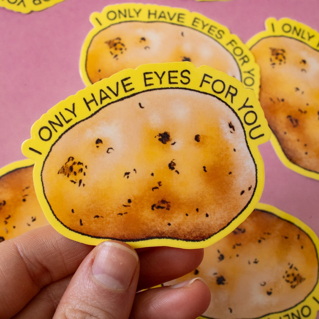 Sticker of a potato with text 'I only have eyes for you' held by a hand on a pink background.