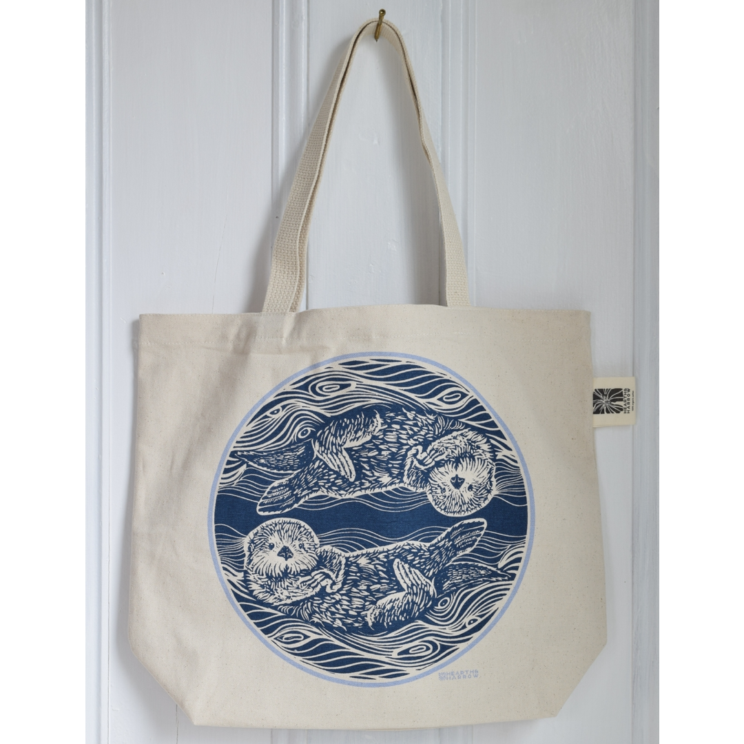 canvas tote bag with two otters in the water printed in blue on the tote