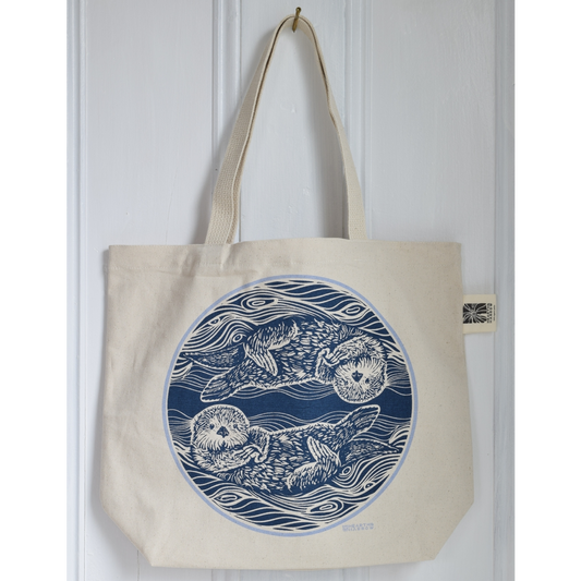 canvas tote bag with two otters in the water printed in blue on the tote