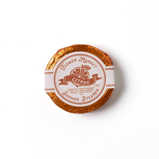Round citrus scented shower steamer with 'Flower Market' branding on a white background