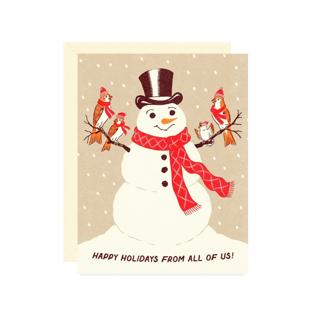 A square holiday greeting card featuring an illustrated snowman wearing a black top hat and red scarf, with small red birds on branches around him, on a beige background. The card reads 'HAPPY HOLIDAYS FROM ALL OF US!' at the bottom.