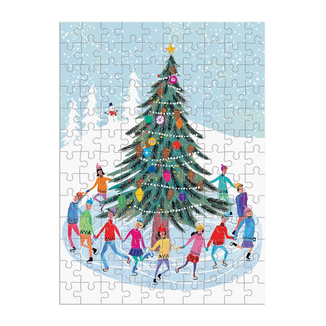 A completed jigsaw puzzle featuring a festive winter scene with a decorated Christmas tree, snow, mountains, and children ice skating in the foreground.
