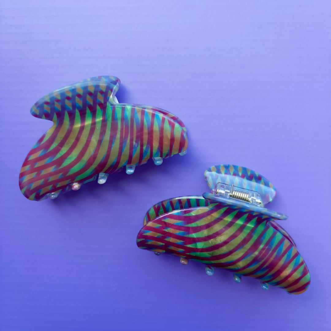 Two colorful striped hair clips on a purple background