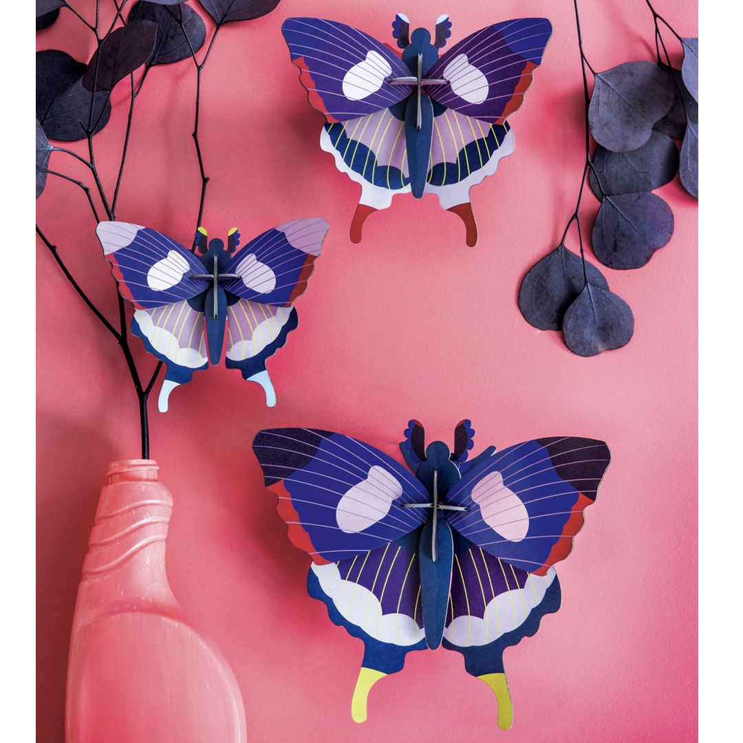 Three 3D paper butterflies on a pink background with a vase and branches.