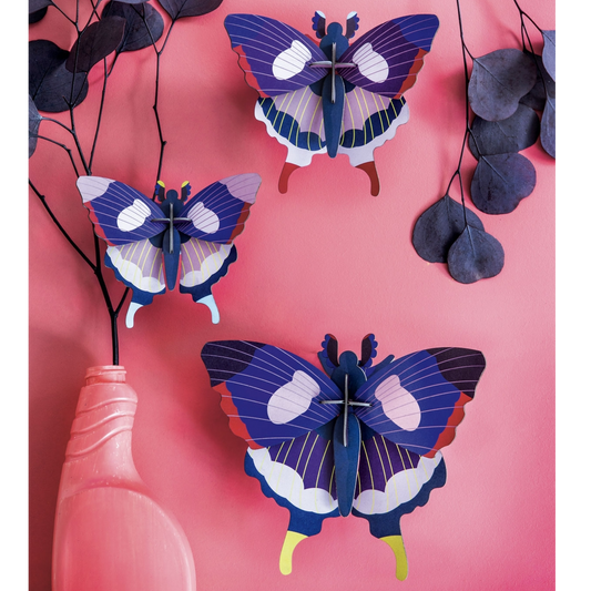 Three 3D paper butterflies on a pink background with a vase and branches.