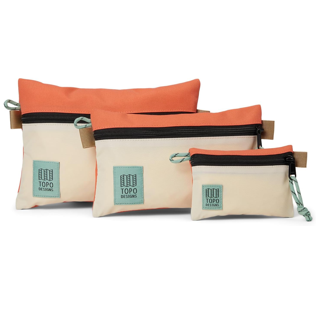 Three Topo Designs pouches in orange and beige on a white background