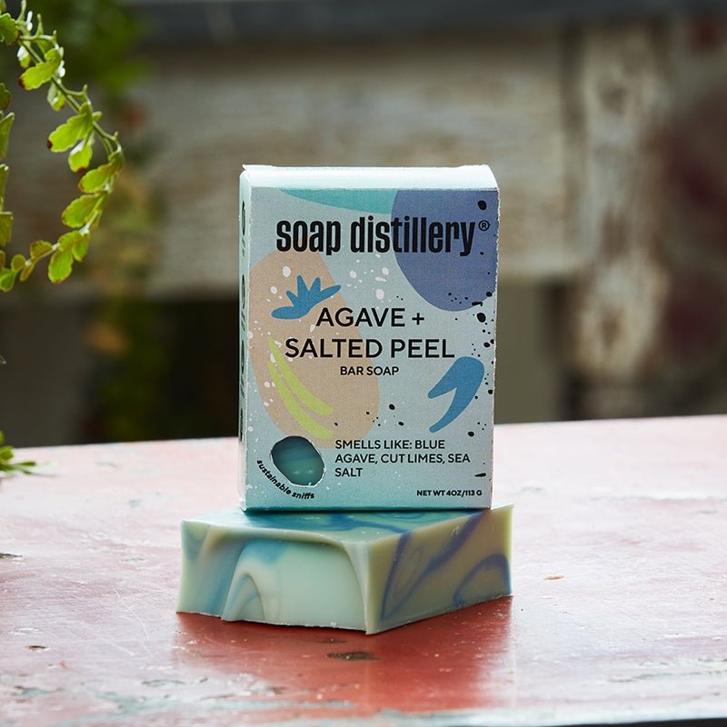 Soap bar with packaging labeled 'Soap Distillery Agave + Salted Peel' on a wooden surface.