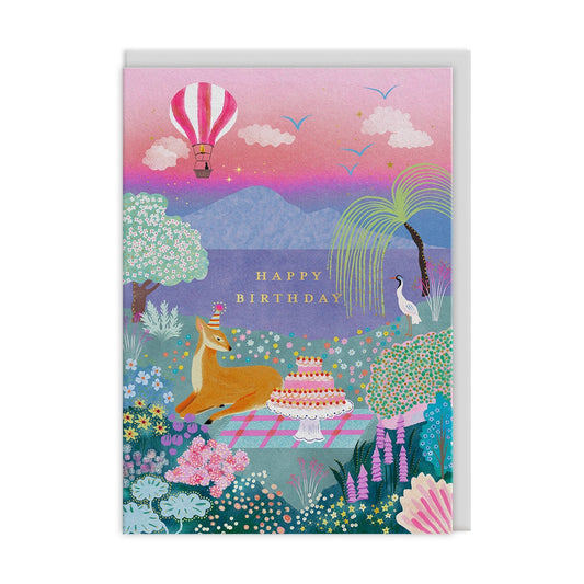 Birthday card with a deer, cake, and hot air balloon in a colorful landscape