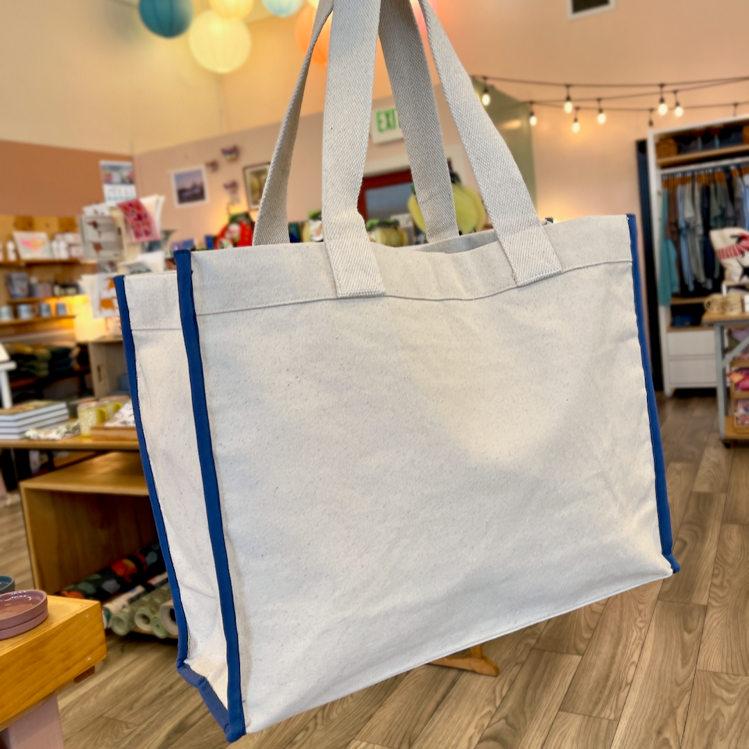 Canvas tote with blue piping. Store interior in background.