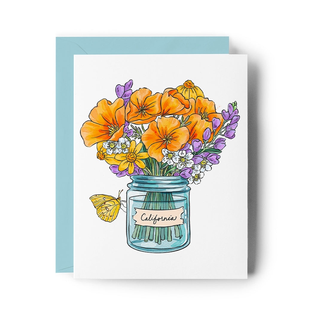 A square greeting card with a white front featuring an illustrated bouquet of orange, purple, yellow, and white flowers in a blue glass jar labeled 'California,' shown with a light blue envelope behind it on a white background.