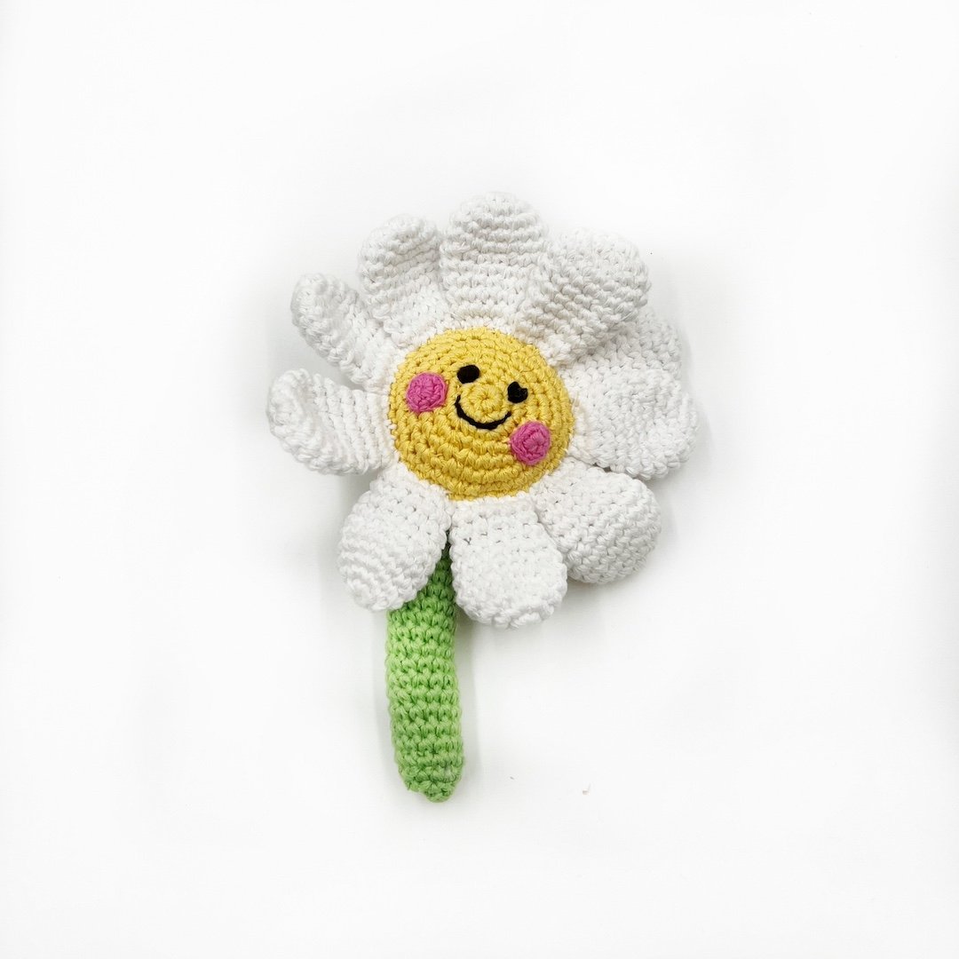 Crocheted daisy flower rattle with a smiley face on a white background
