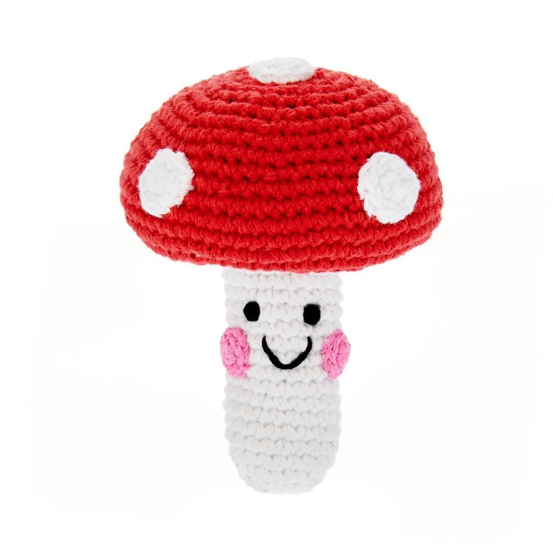 Crocheted mushroom toy with a red cap and white spots on a white background