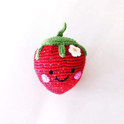 Crocheted strawberry rattle with a smiling face on a white background