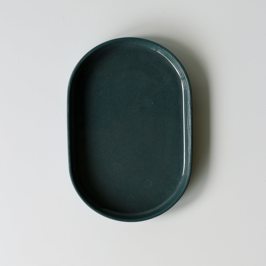 Dark denim blue oval shaped ceramic tray on a light gray background
