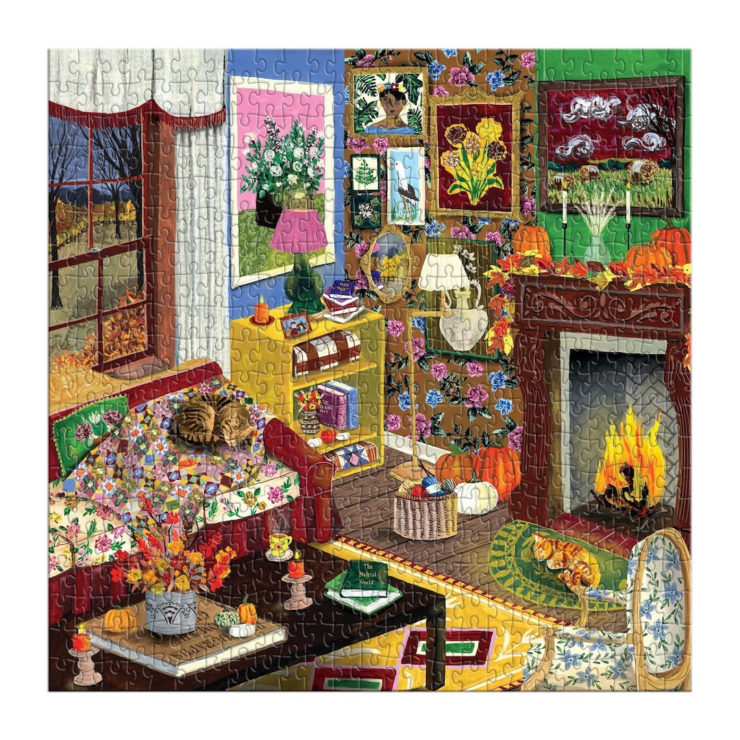 A completed jigsaw puzzle depicting a cozy, colorful autumn living room scene with a fireplace, cat on a couch, flowers, pumpkins, and framed art.