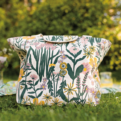 Floral-patterned bag on grass with blurred greenery in the background