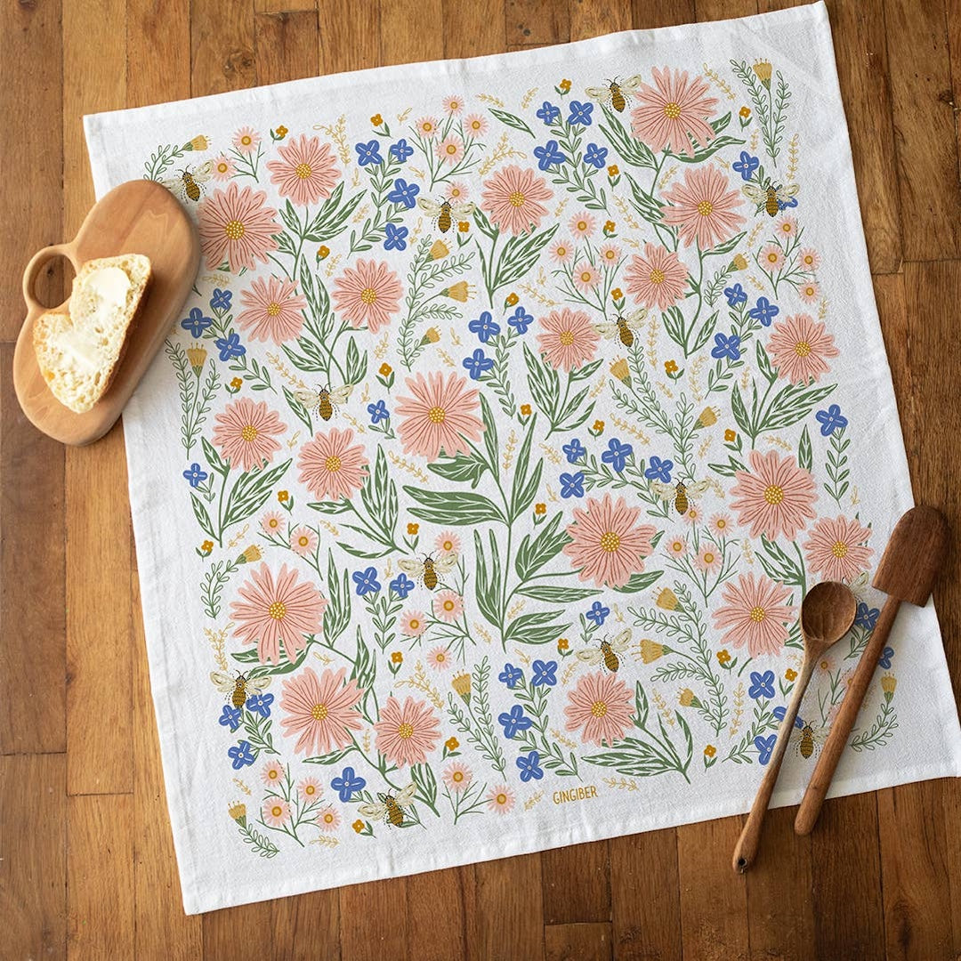 Floral patterned towel on a wooden surface with wooden spoons and a light.