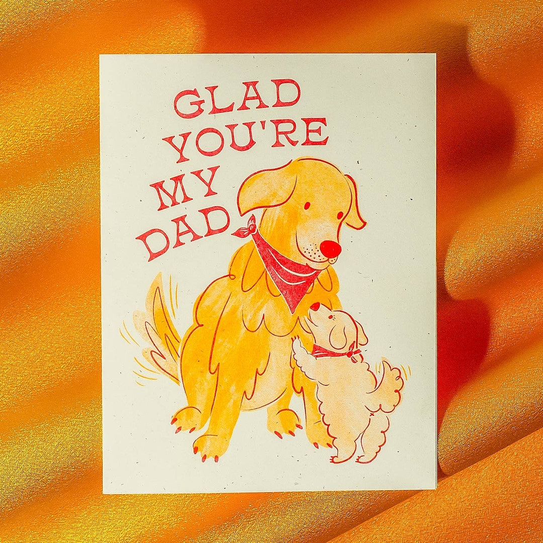 Card with two dogs and text 'Glad you're my dad' on a textured orange background