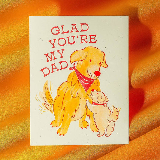 Card with two dogs and text 'Glad you're my dad' on a textured orange background