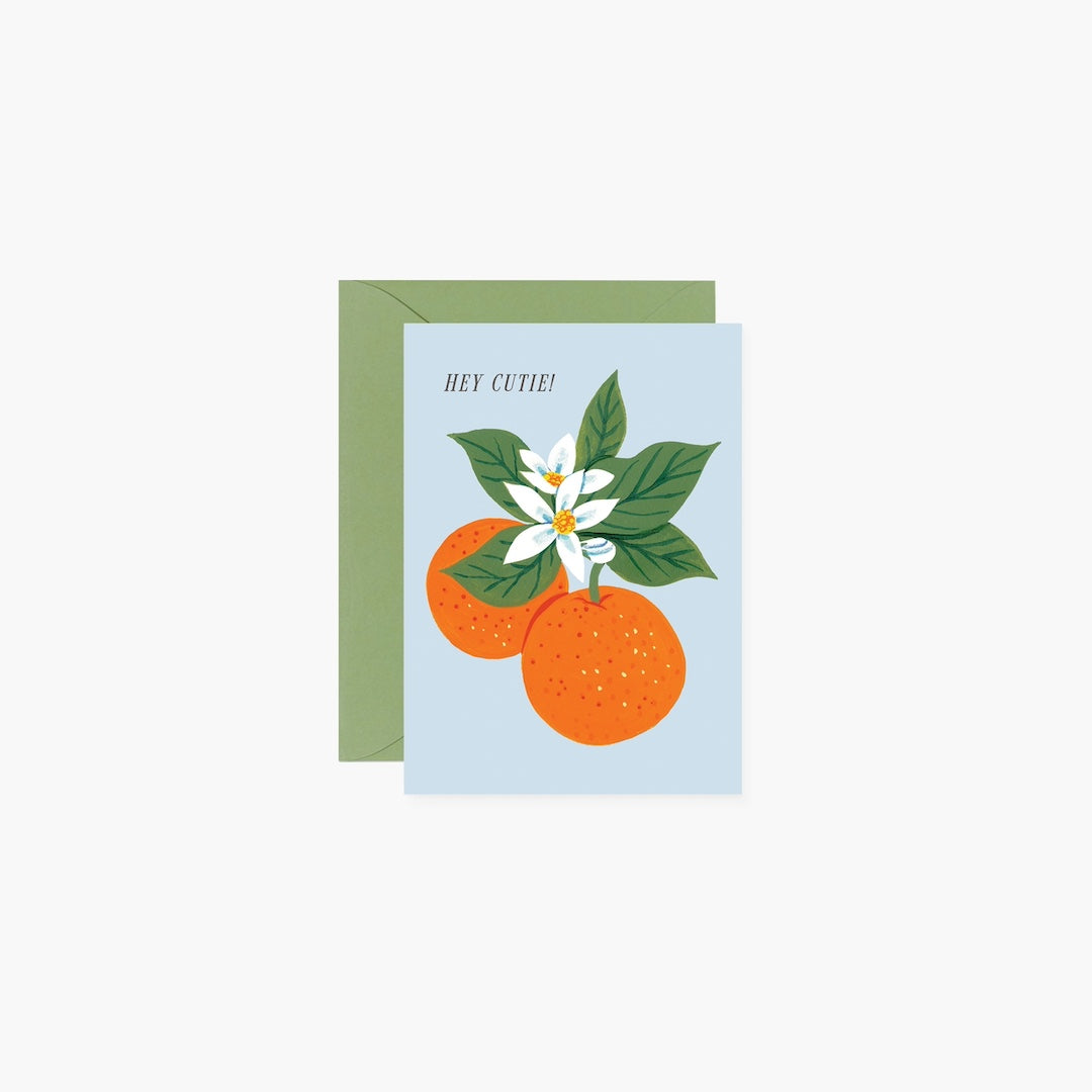 Greeting card with oranges and a flower on a light blue background with text that reads hey cutie and a green envelope.