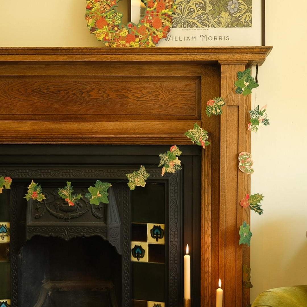 Decorative garland with holly leaves and berries on a fireplace mantle.