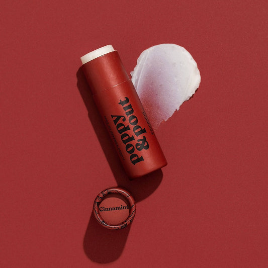 Tube of Lip Balm from Poppy & Pout in the scent Cinnamint on a red background