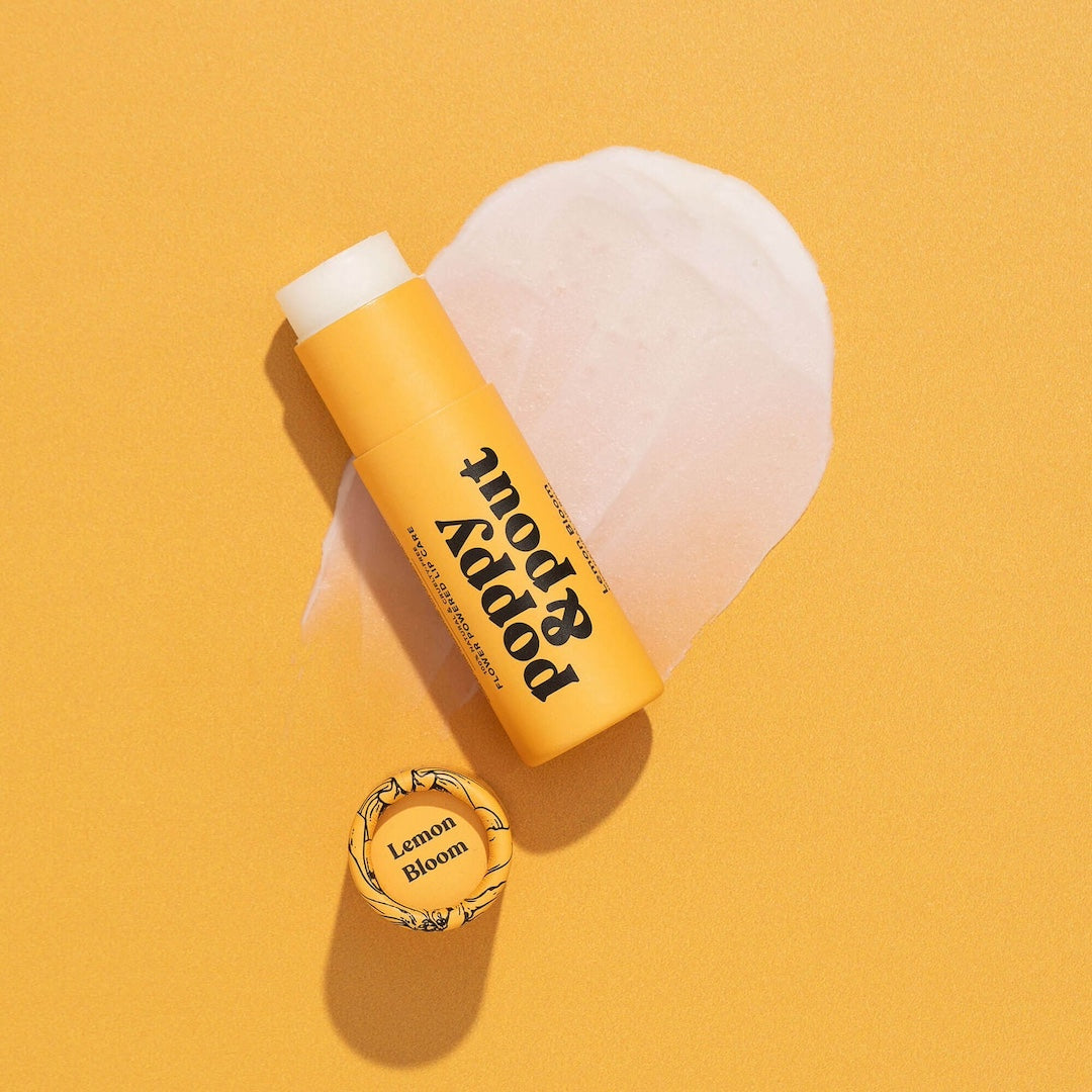 Tube of Lip Balm from Poppy & Pout in the scent Lemon Bloom on a yellow background