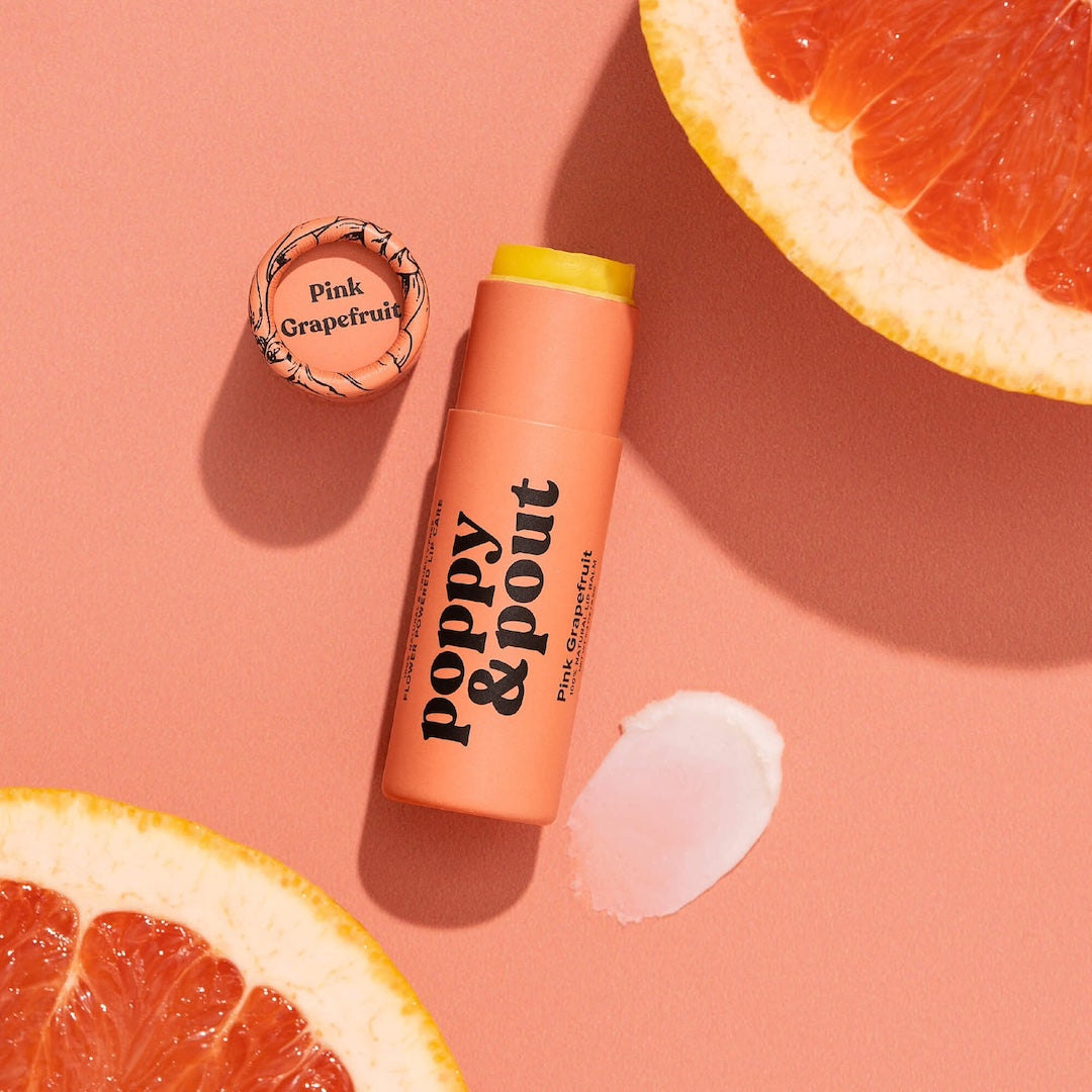 Tube of Lip Balm from Poppy & Pout in the scent Pink Grapefruit on a pink background