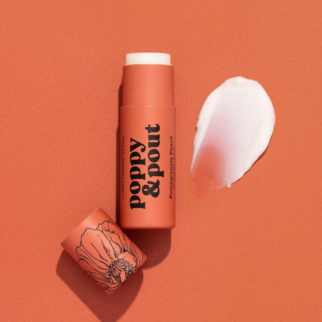 Tube of Lip Balm from Poppy & Pout in the scent Pomegranate Peach on a red background