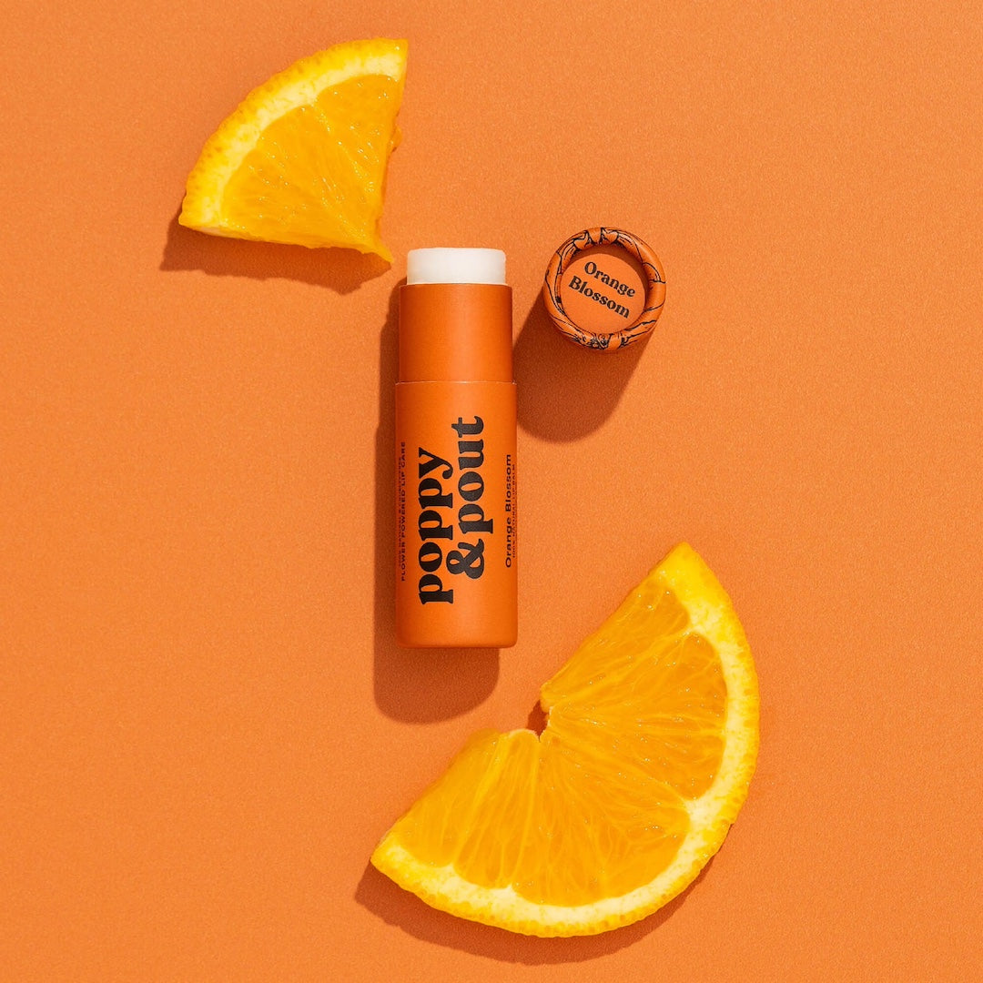Tube of Lip Balm from Poppy & Pout in the scent Orange Blossom on an orange background
