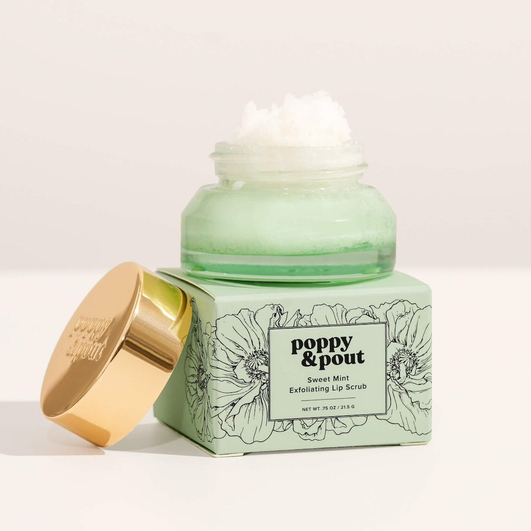 Green jar of poppy & pout lip scrub with gold lid on a white background