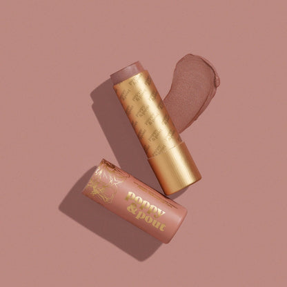 Poppy & Pout Charlie lip tint in a gold tube on a mauve background