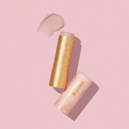 Poppy & Pout Daisy lip tint in a gold tube on a pink background