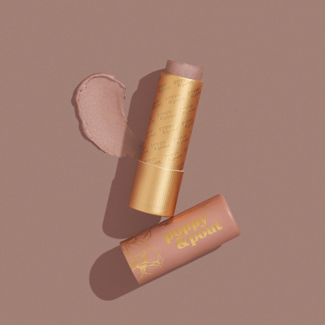 Poppy & Pout Faye lip tint in a gold tube on a dark mauve background
