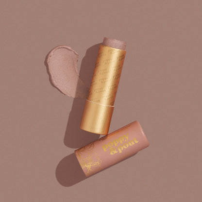 Poppy & Pout Faye lip tint in a gold tube on a dark mauve background