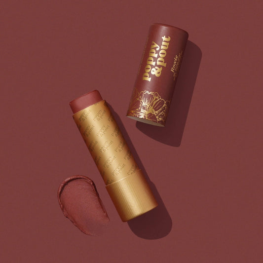 Lip Tint Poppy & Pout Roxie in a gold tube on a dark red background