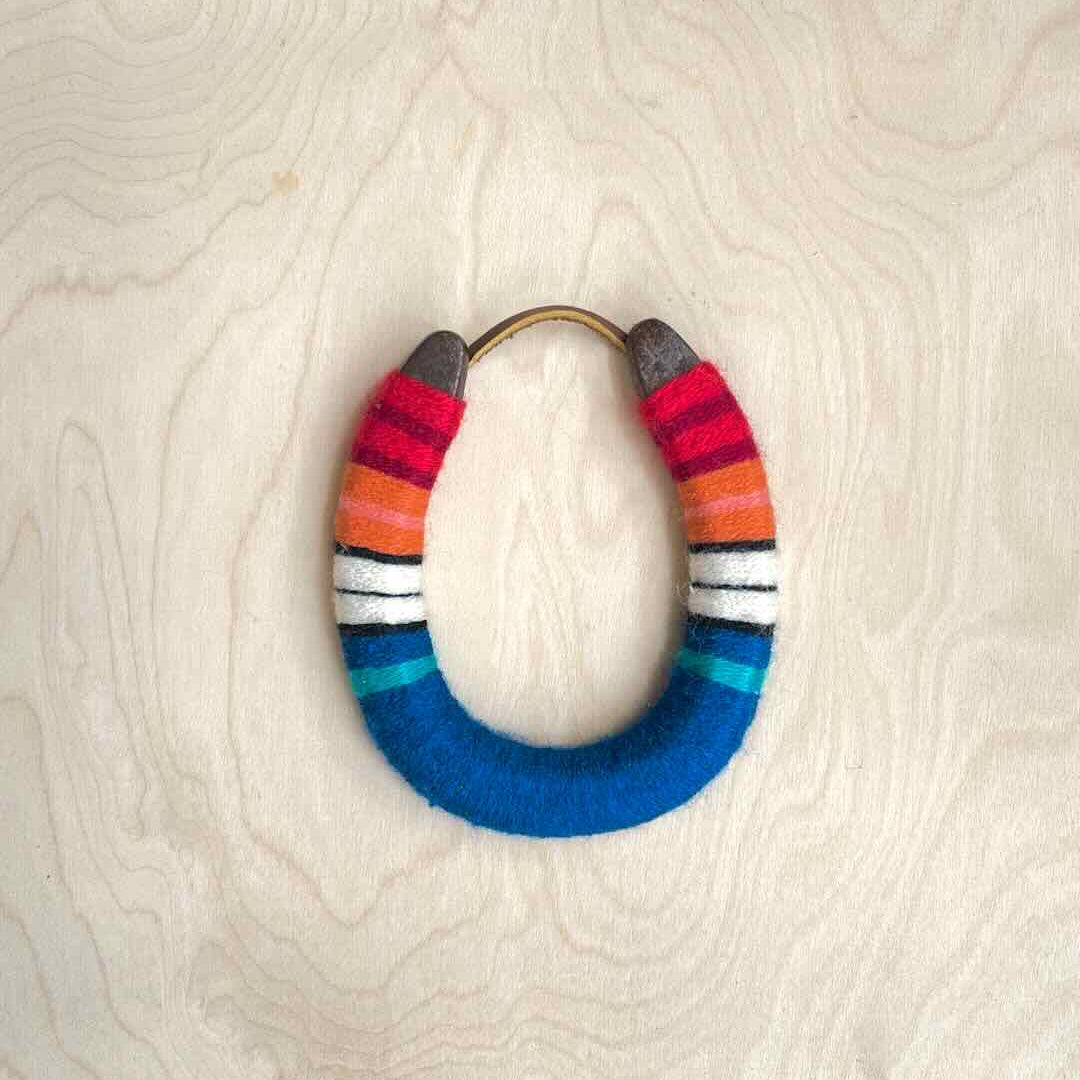 Colorful yarn wrapped horseshoe with red top and blue bottom.