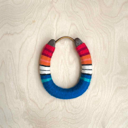 Colorful yarn wrapped horseshoe with red top and blue bottom.
