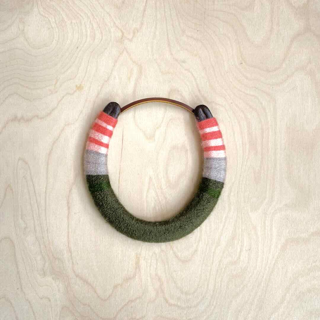 Colorful yarn wrapped horseshoe with pink top and green bottom.