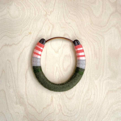 Colorful yarn wrapped horseshoe with pink top and green bottom.