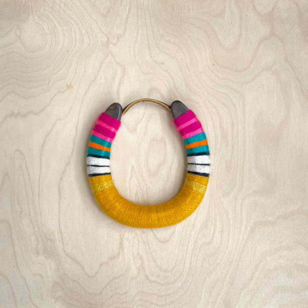 Colorful yarn wrapped horseshoe with pink top and golden yellow bottom.